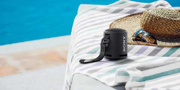 A portable speaker on a sun lounger near a pool.